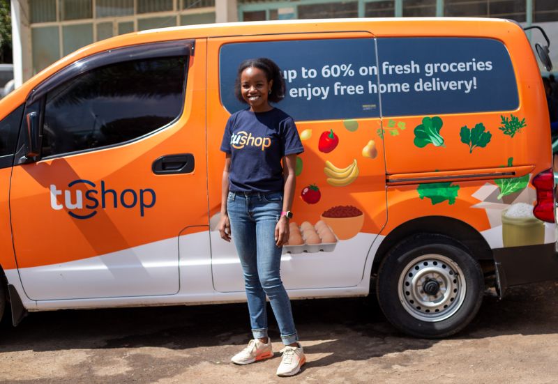 A Tushop team member standing in front of an orange Tushop delivery van